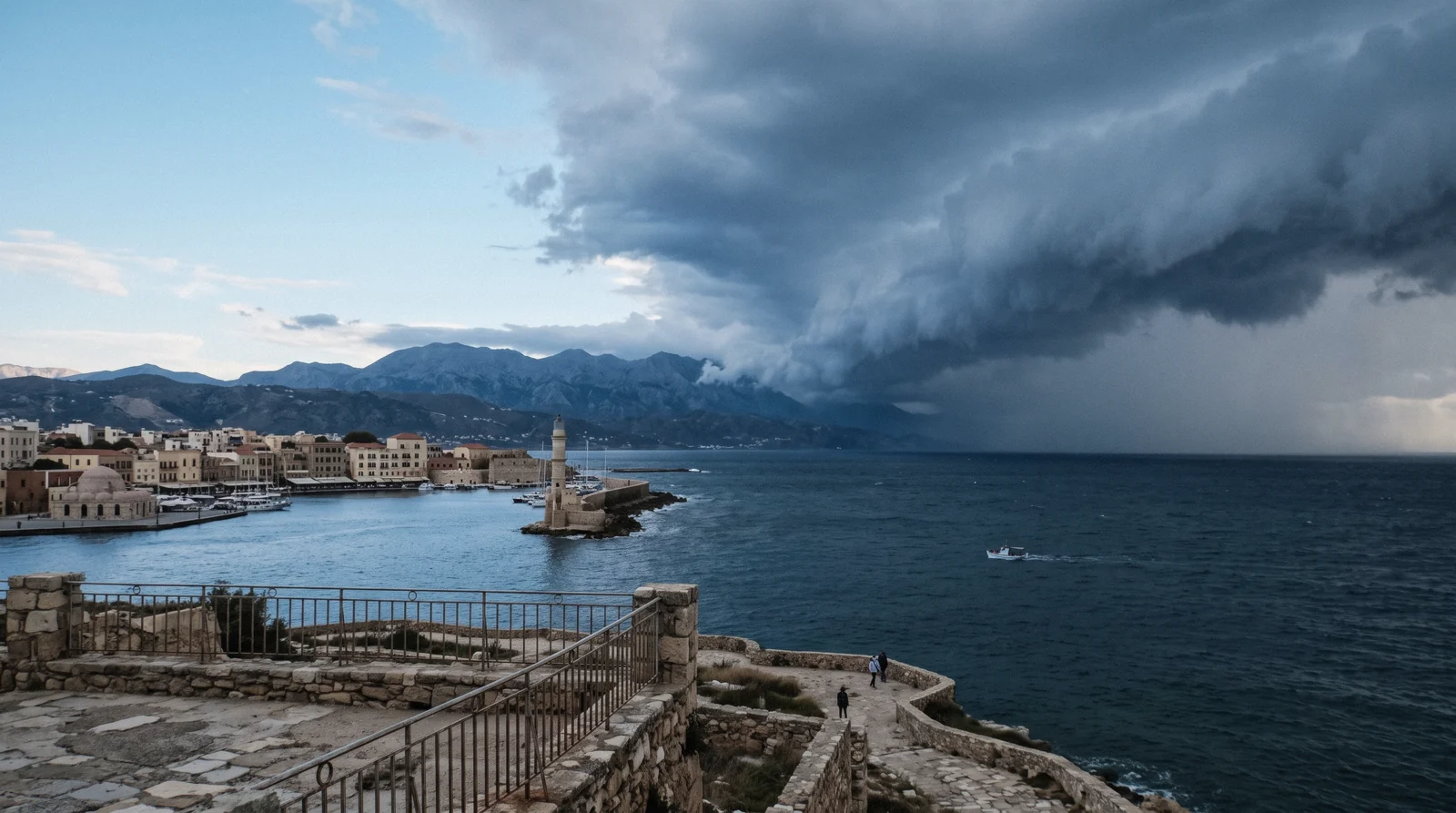 Storm clouds over the White Mountains above a blue Aegean bay, showing Crete weather changing fast on the west coast